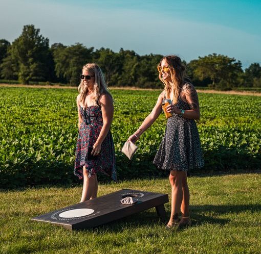 Two women enjoying a game of cornhole outdoors on a sunny day.
